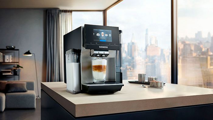 Ein Siemens Kaffeevollautomat mit einem integrierten Milchbehälter. Daneben befindet sich weiteres Kaffeezubehör.