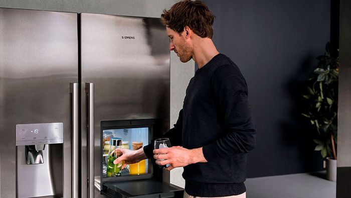 Ein Mann bedient eine Siemens Kühl-Gefrier-Kombination Side-by-Side