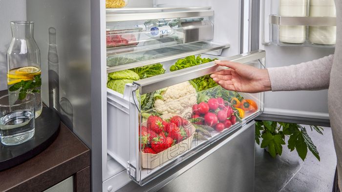 Ein Mensch öffnet eine Kühlschublade mit Obst und Gemüse in einem Siemens Kühlschrank.