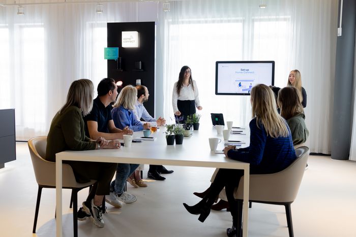 Groep mensen aan tafel volgt training over Home Connect
