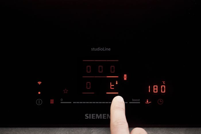 Siemens Kochfeld von oben, das gerade bedient wird. Eine Person verwendet die touchSlider Funktion.