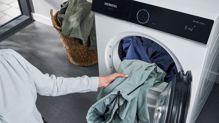 Frau nimmt Wäsche aus Waschmaschine