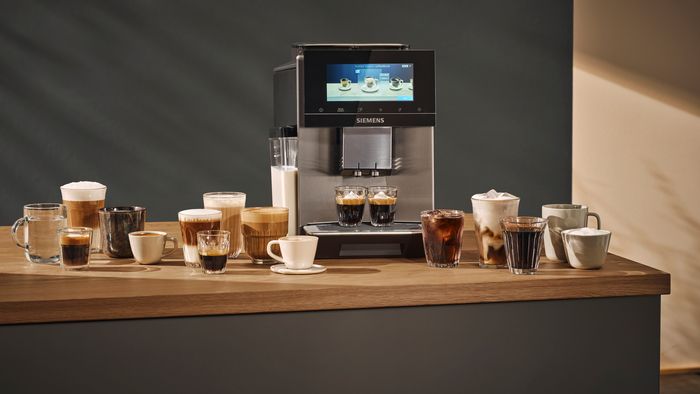 Siemens Coffeeworld - pohled zepředu na plně automatický kávovar Siemens EQ.9 plus s různými kávovými nápoji