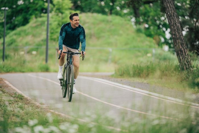 Alexander Kumptner, der Koch Influencer, fährt mit einem Fahrrad auf einem Weg im Freien.