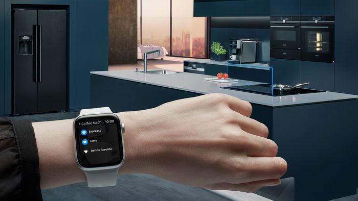 Moderní kuchyně s chytrými domácími spotřebiči a smartwatch ovládání kávovaru.
