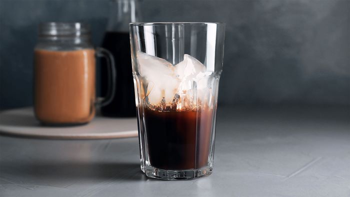 In ein Glas mit Cold Brew Kaffee wird Milch hinzugefügt.