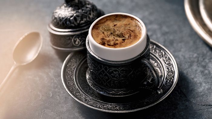 Frischer türkischer Kaffee in einer orientalisch gestalteten Tasse mit Deckel.