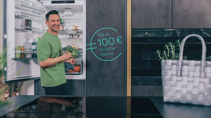 Eine Frau steht an einer geöffneten freistehenden Kühl-Gefrier-Kombination von Siemens.