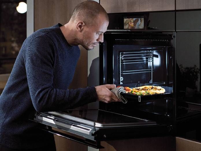 Ragazzo che inforna una pizza nel forno Siemens