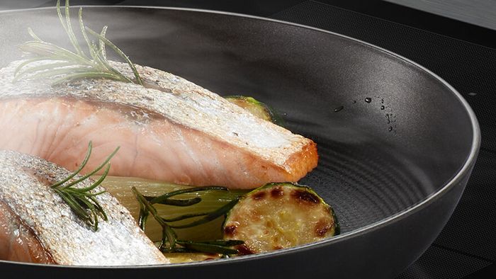 Cottura di salmone e verdure in una padella in alluminio