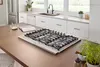 Modern kitchen featuring a built-in Bosch gas cooktop on a wooden island with nearby plants.