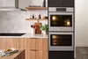 Modern kitchen with built-in Bosch double wall oven, wooden cabinets, and open shelves.