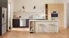 Modern kitchen with Stainless Steel appliances, light wood cabinets, black appliances, and bar stools.