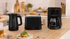 Küchentheke mit Wasserkocher, Toaster und Kaffeemaschine; Frühstücksartikel daneben.