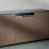 Holzschrank mit schwarzer Arbeitsplatte, geschlossenen Türen und einem sichtbaren elektronischen Gerät.