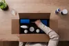 Top-down view of a person unboxing a care package with cleaning products on a wooden desk.
