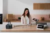 A smiling woman stands in a modern kitchen, holding a component of a Bosch dishwasher.
