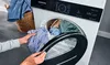 A person is loading a shirt into a tumble dryer