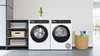 Three Bosch white laundry appliances: a washing machine on the left and two dryers on the right, showcasing sleek designs and digital controls.