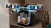 A sleek coffee machine on a stone countertop, brewing espresso alongside various coffee cups.