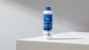 Blaue Flasche mit Reinigungsmittel auf weißer Oberfläche.