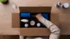 Top-down view of a person unboxing a care package with cleaning products on a wooden desk.