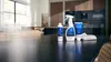 Productos de limpieza sobre la encimera de la cocina: botella pulverizadora, desinfectante, papel de cocina y esponja.