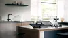 Cocina moderna con elegantes electrodomésticos negros, encimera de madera y una decoración minimalista.