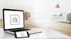 Laptop and mobile device displaying envelope icon, modern living room interior in background.