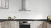 Modern kitchen with Bosch range hood, stove, and rustic cabinets on a white brick wall.