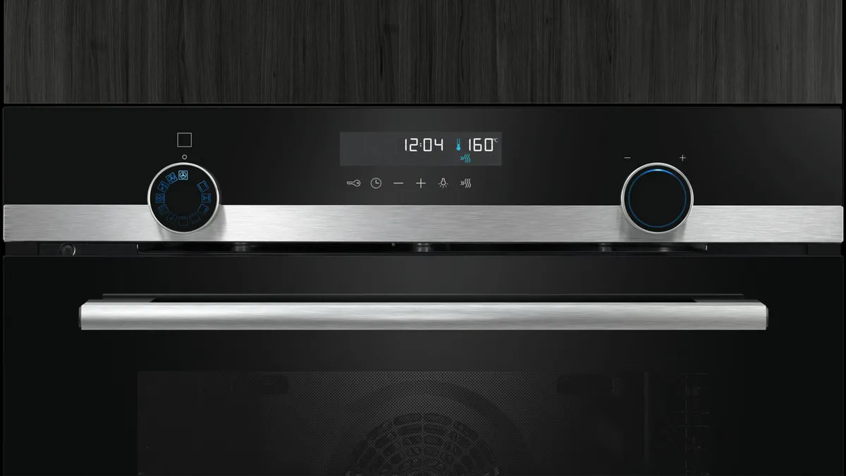 En modern ugnskontrollpanel med digital display, temperaturinställningar och rostfria accenter på en stilren svart bakgrund.