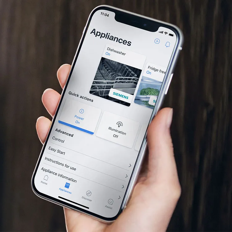 Personne tenant un smartphone avec l'écran visible, assise les jambes croisées à l'intérieur