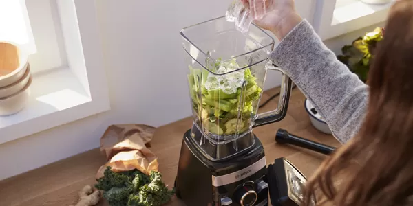 Three Bosch blenders on a kitchen counter, each filled with vibrant fruits and vegetables, showcasing their sleek design and functionality.