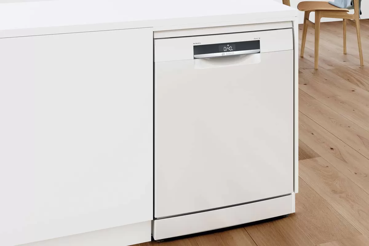 Un elegante lavavajillas encastrado de color blanco con un diseño moderno y pantalla digital, colocado sobre un suelo de madera clara en una cocina con estilo.