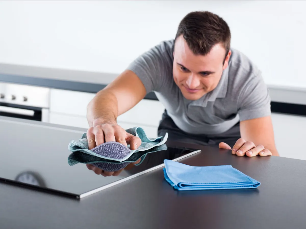 Person using cleaning products on hob