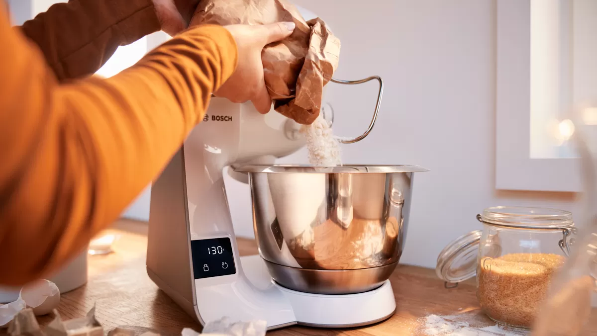 Bir mutfakta yiyecek hazırlamak için bir stand mixer kullanan kişi.