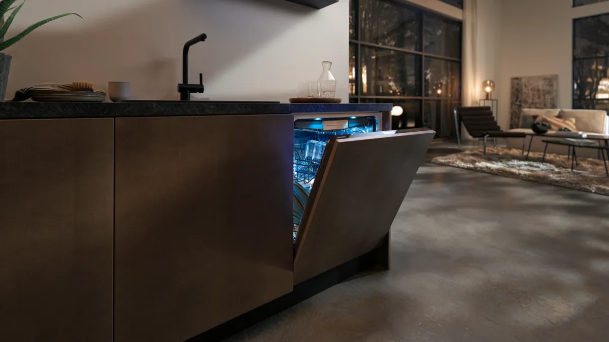 Modern kitchen with dark cabinets, sink, and appliances visible in dimly lit room.