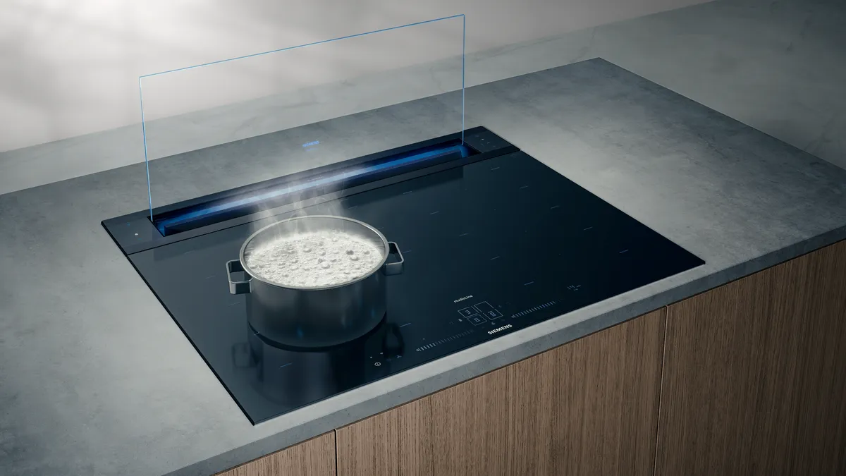 Sleek kitchen countertop with induction cooktop, steam rising from a pot.