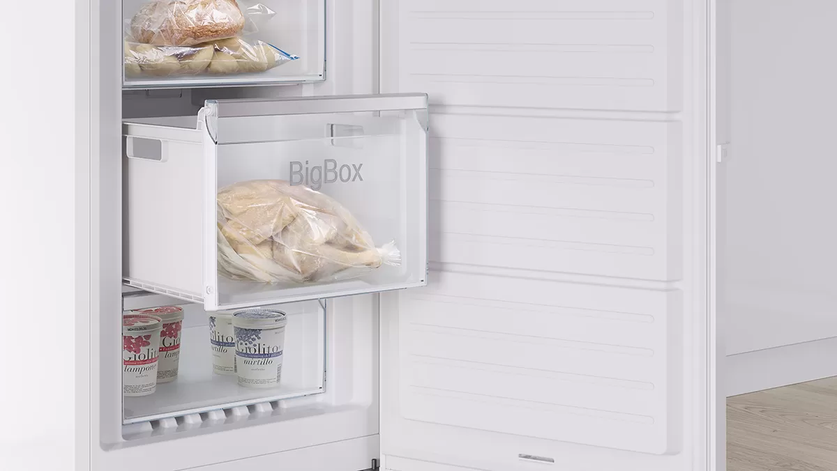 Ein offener Gefrierschrank präsentiert eine durchsichtige BigBox-Schublade mit gefrorenem Brot und darunter zwei Eisbehälter