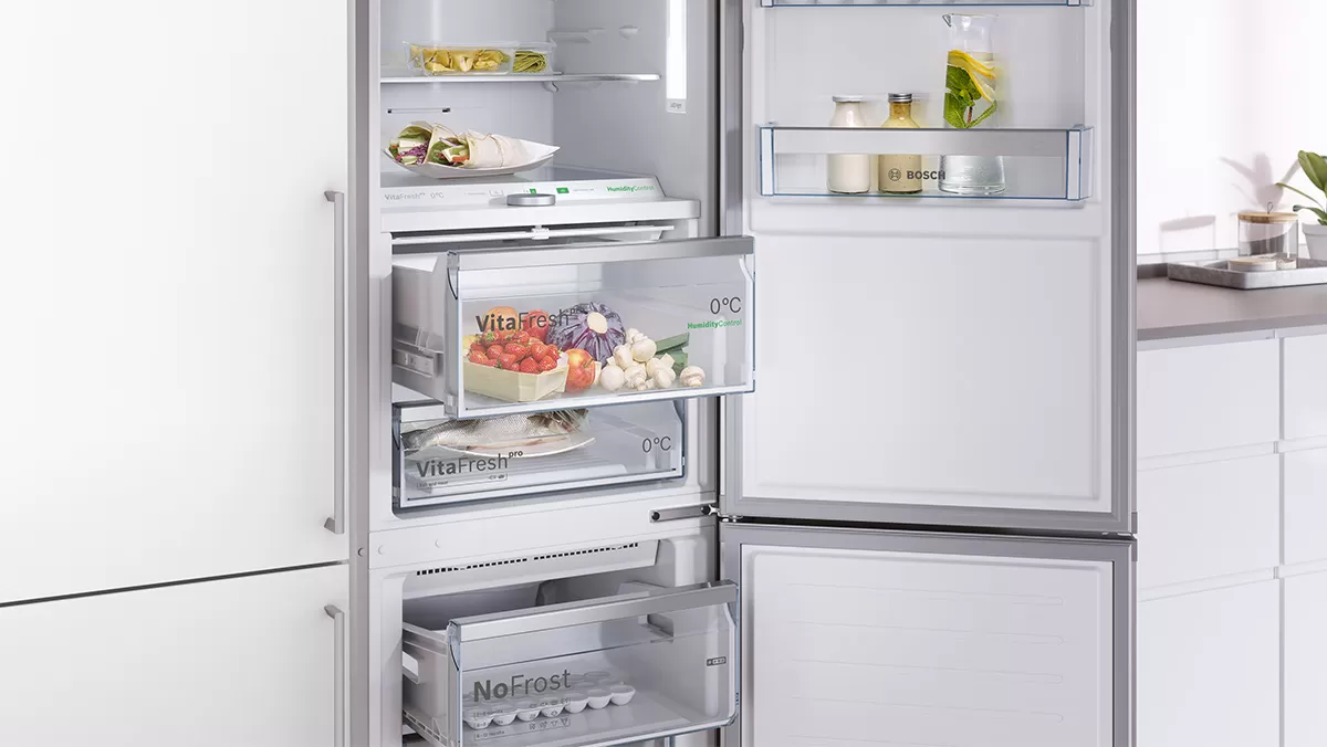 Réfrigérateur encastrable Bosch ouvert, avec tiroirs VitaFresh et NoFrost remplis d’aliments.