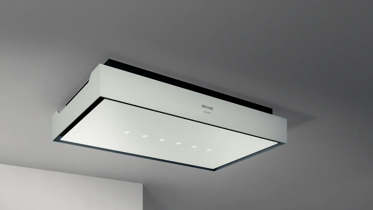 Moderne Küche mit einer eleganten Holzinsel, Induktionskochfeld und minimalistischer Deckenhaube vor einer dunkelblauen Wand.