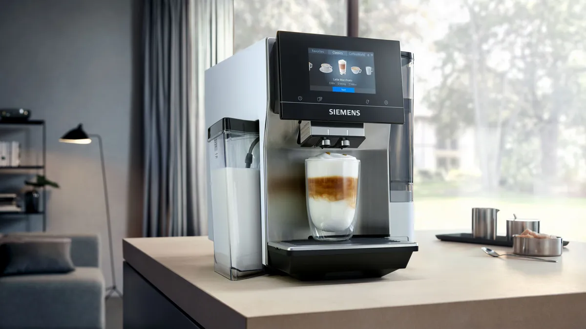 Siemens kavni aparat z ravnokar pripravljenim kavnim napitkom z mlekom.