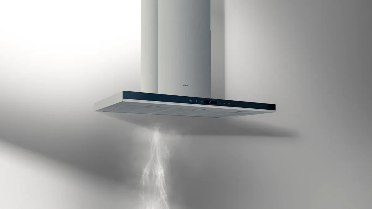 Cucina moderna con un'elegante isola in legno, dotata di piano cottura integrato, e una cappa in acciaio inox su una parete blu scuro.