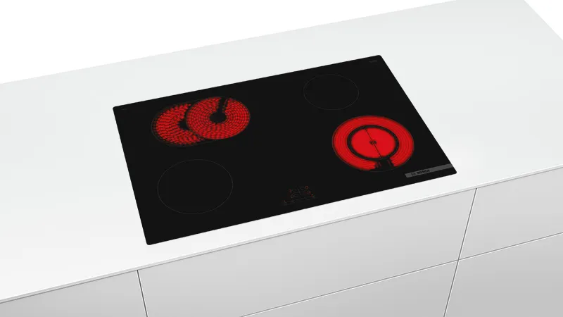A modern black glass-ceramic hob with four burners, two glowing red to indicate heat. The sleek, minimalist design is set into a white countertop.