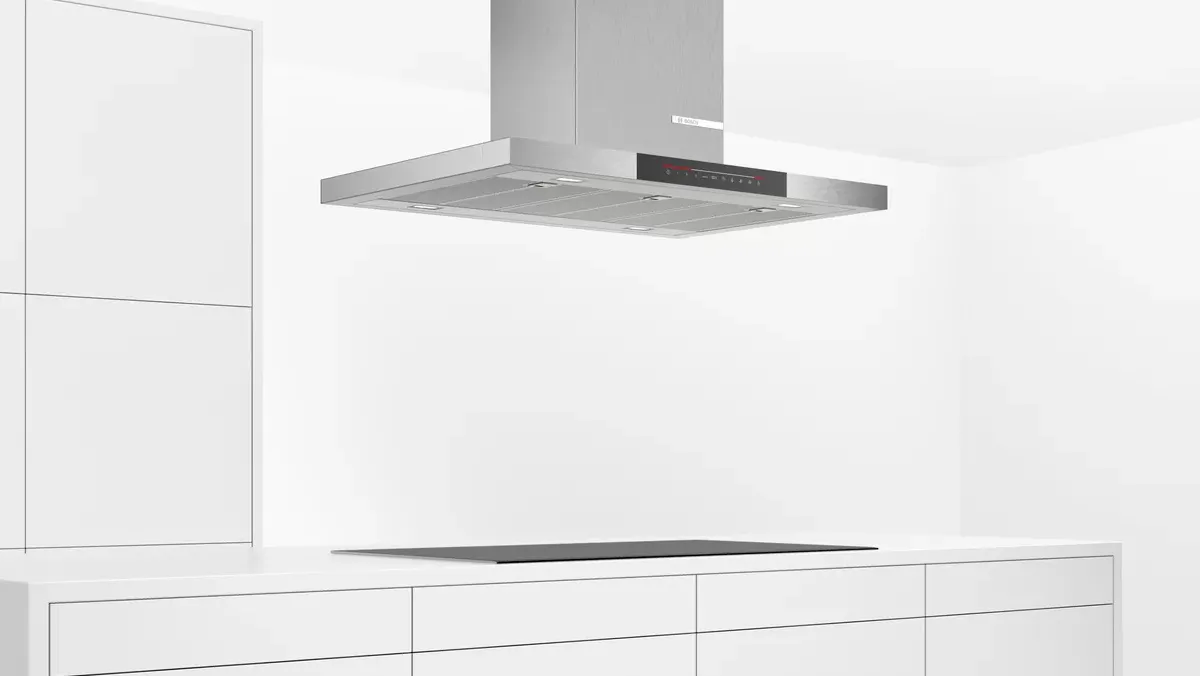 Modern kitchen featuring a stylish hood above a wooden island, with a pot and fruit bowl.