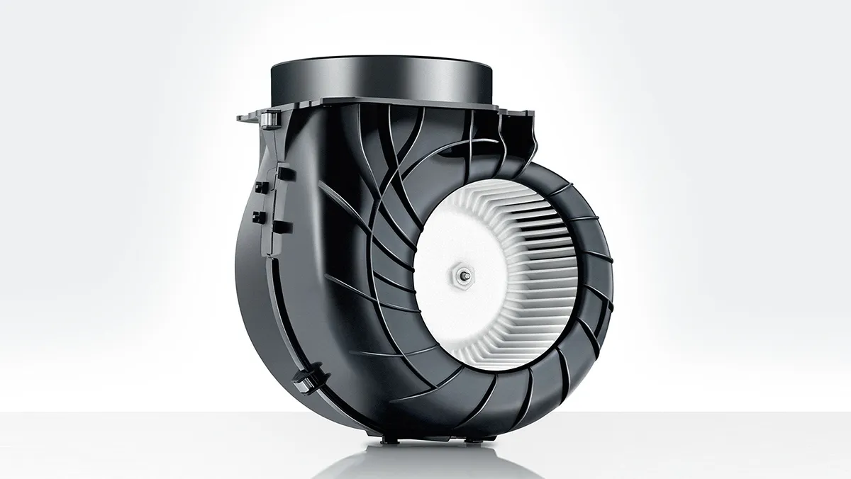 A sleek black kitchen hood hovers above a steaming pot, while a cat lounges on the countertop.