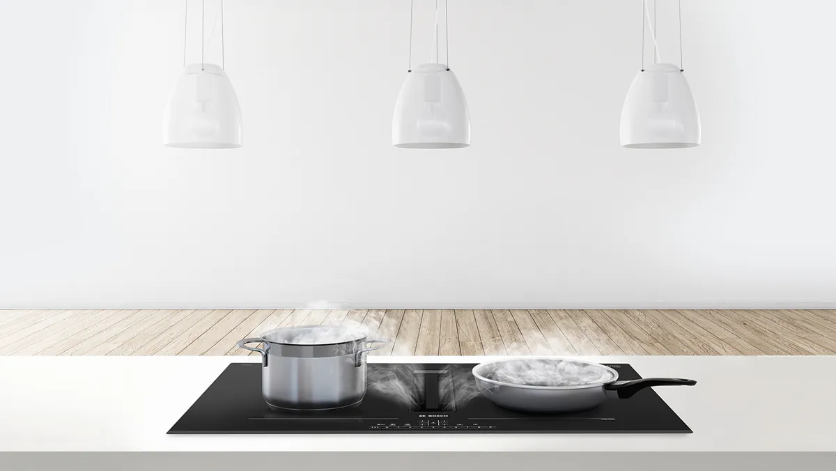 A modern kitchen, featuring boiling pasta and sizzling shrimp on an induction cooktop.