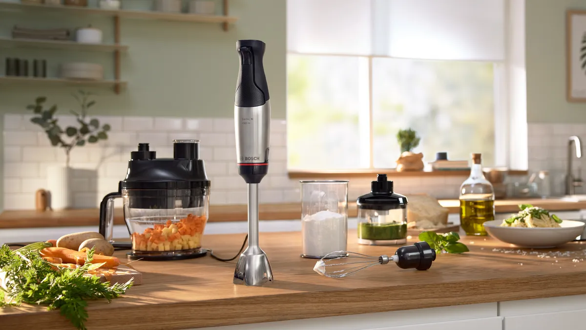 Bosch ErgoMaster -sauvasekoitin ja sen lisäosat keittiön työtasolla. Ympärillä tuoreita aineksia.