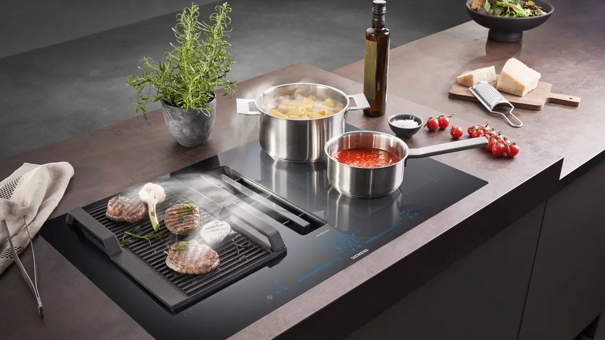 Siemens häll med inbyggd fläkt där burgare grillas, pasta kokar och tomatsås sjuder medan ångan sugs in effektivt.