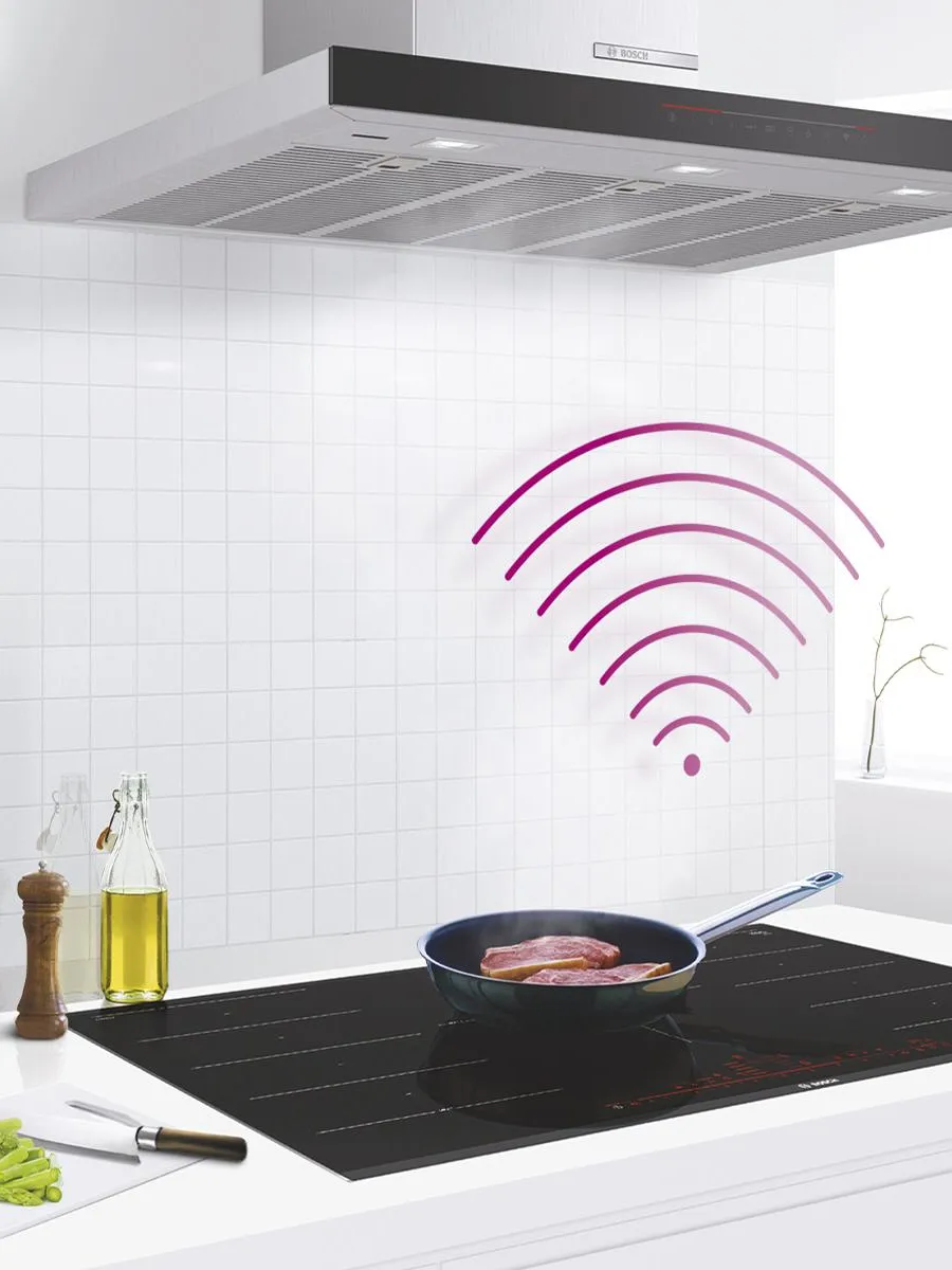 A person holds a smartphone displaying a smart appliance app in a modern kitchen.